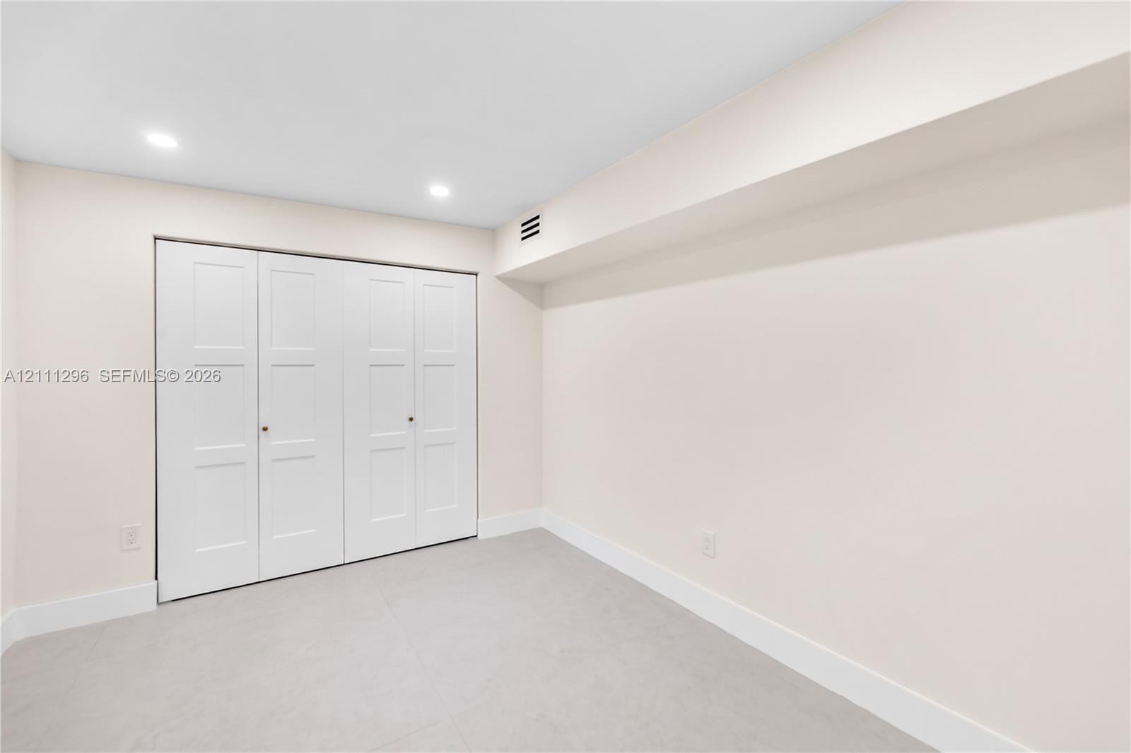 Neutral-toned interior space featuring recessed ceiling lighting and a four-panel bi-fold closet
