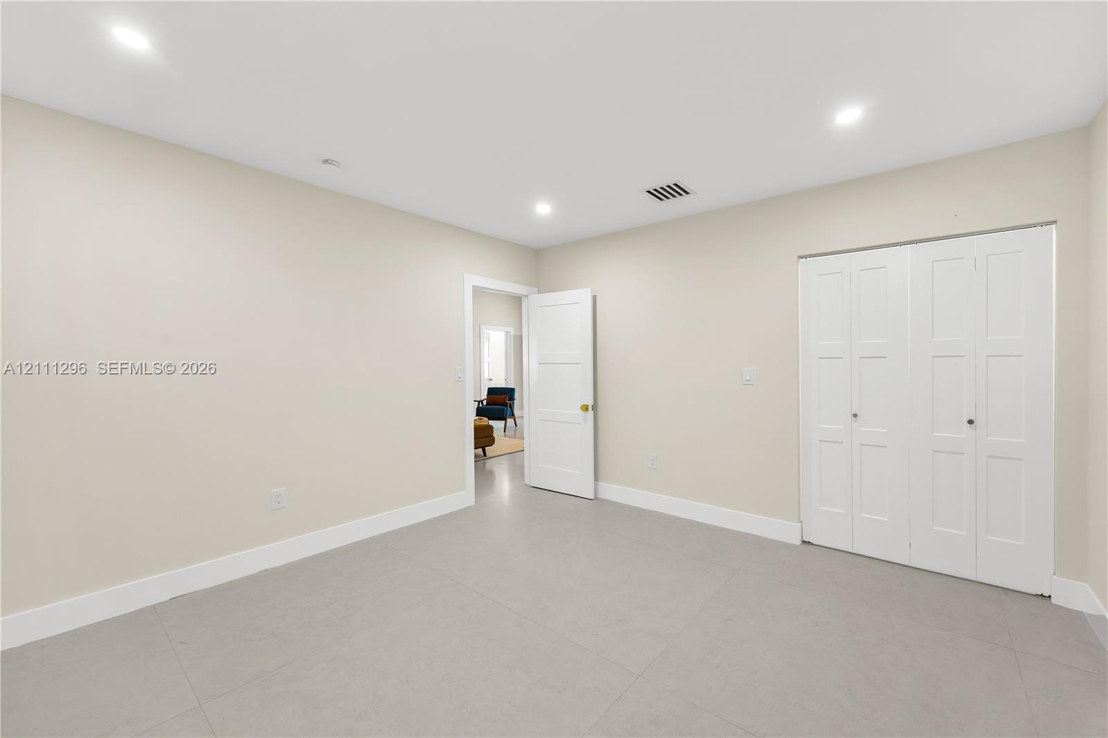 Neutral-toned room featuring recessed lighting, smooth-finish flooring, and a multi-panel door closet with white finish