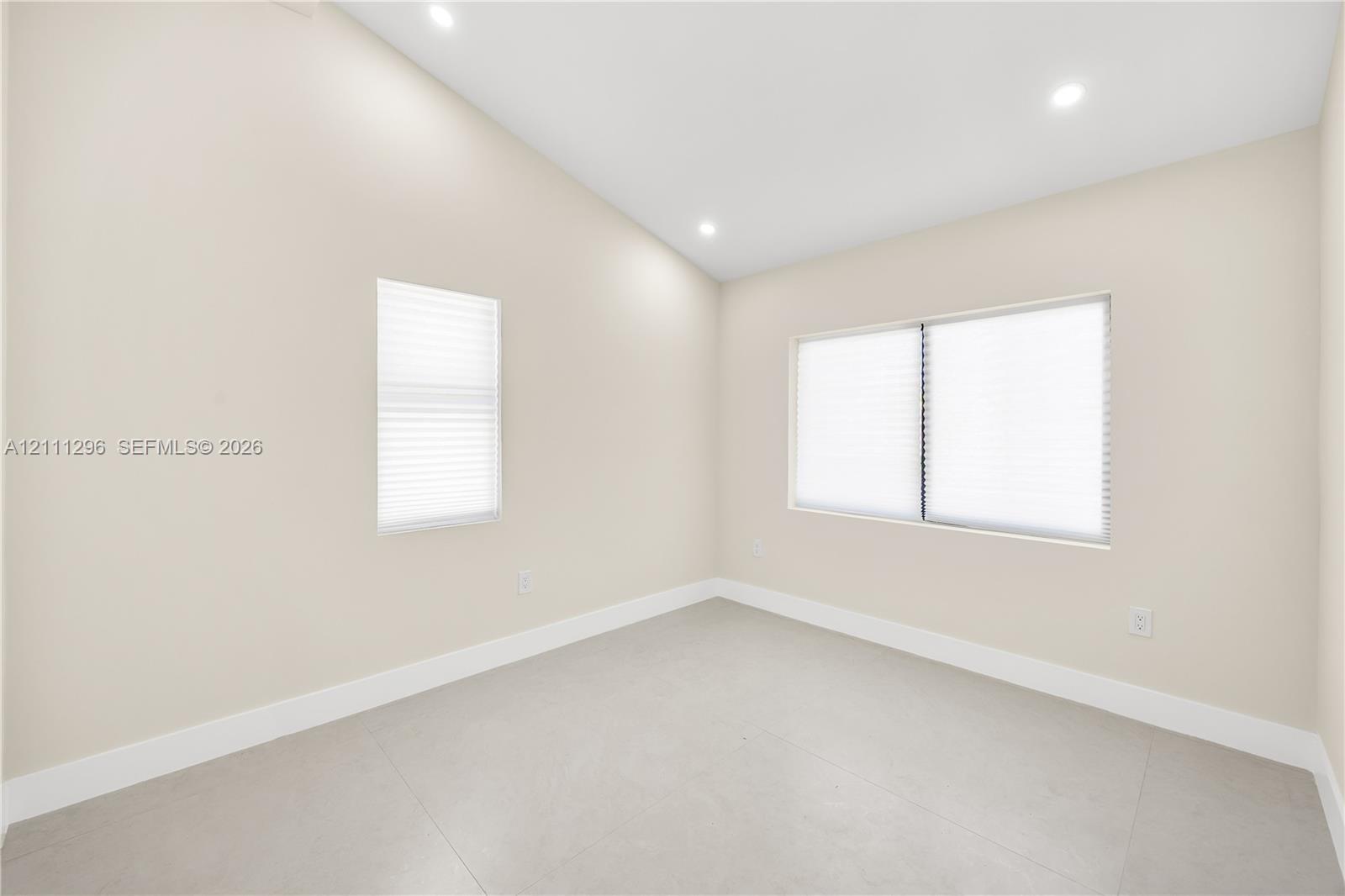 Vaulted ceilings featuring recessed lighting, large-format neutral tile flooring, and multiple windows with integrated blinds