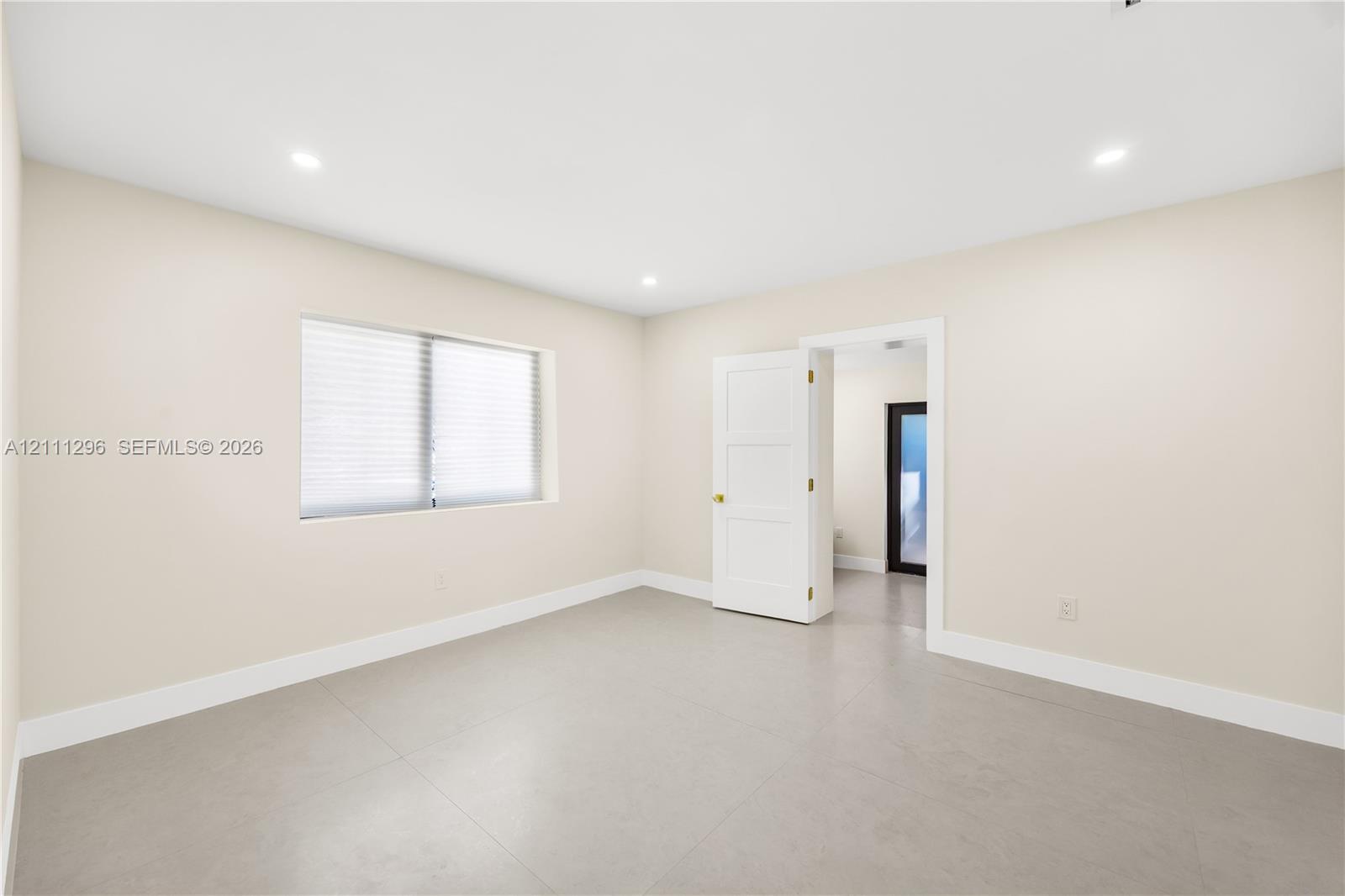 Neutral-toned tile flooring, recessed ceiling lighting, and a three-panel interior door