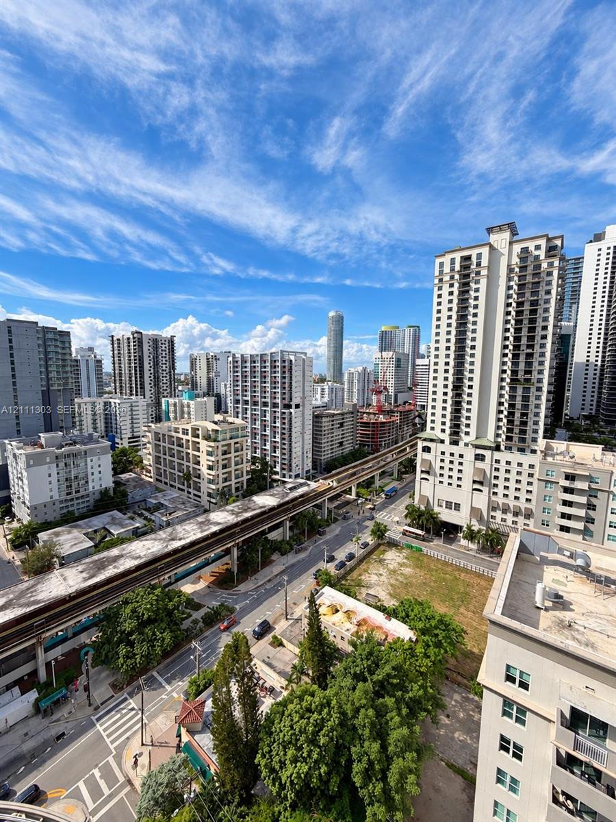 High-rise perspective featuring an urban cityscape, elevated rail infrastructure, and multi-story residential architecture