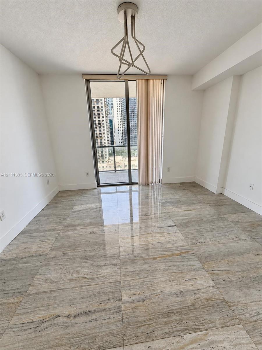 Polished stone flooring, geometric metal pendant lighting, and floor-to-ceiling glass sliding doors leading to a private balcony Polished stone flooring, geometric metal pendant lighting, and floor-to-ceiling glass sliding doors leading to a private balcony
