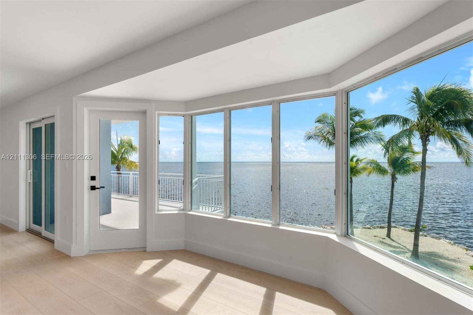 Bay window featuring floor-to-ceiling glass, wood-finish flooring, glass-paneled door, and coastal waterfront exposure
