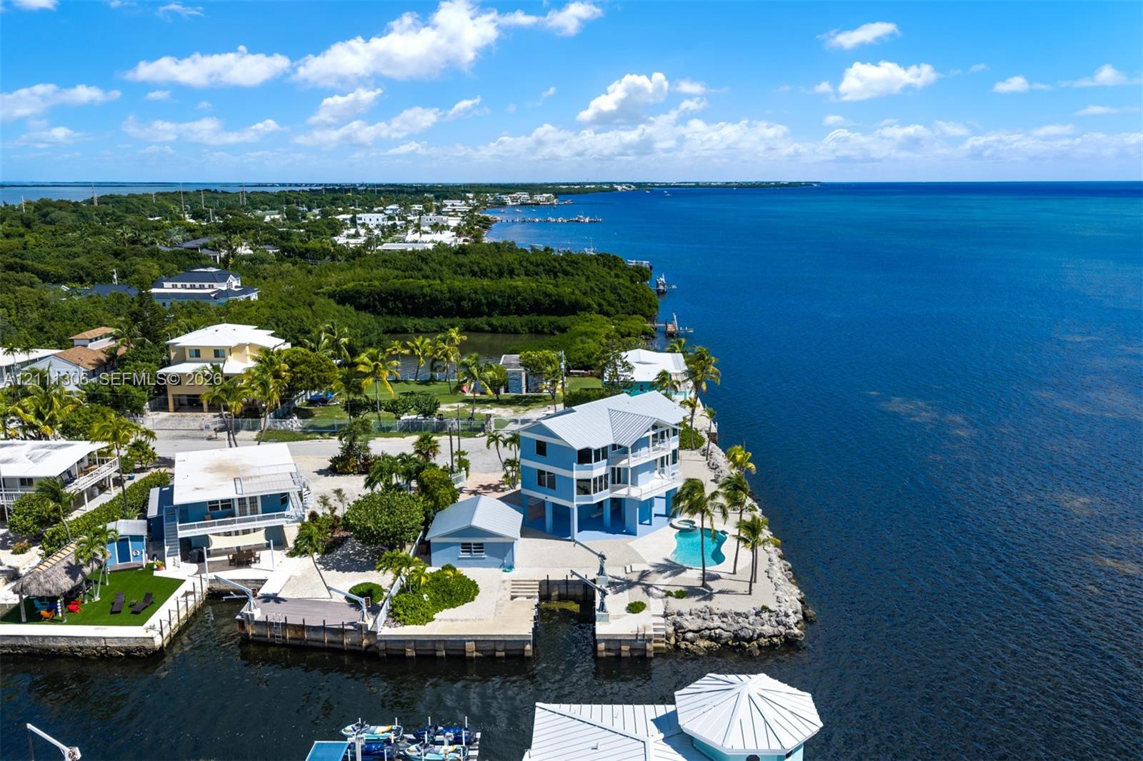 Waterfront property featuring a multi-story home, private boat dock, in-ground swimming pool, and stone-surfaced outdoor area