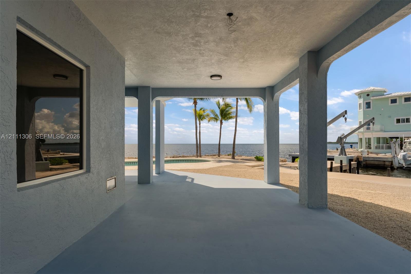 Covered patio featuring concrete flooring, structural support pillars, recessed ceiling lighting, and waterfront access