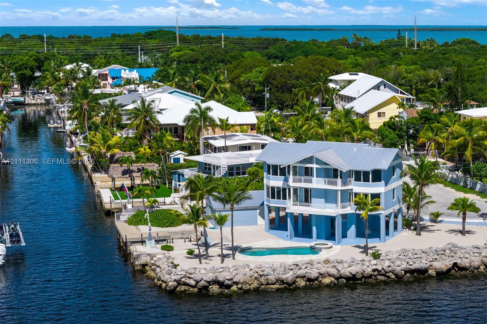 Waterfront residence featuring a metal roof, stacked porches, private swimming pool with integrated spa, and direct canal access