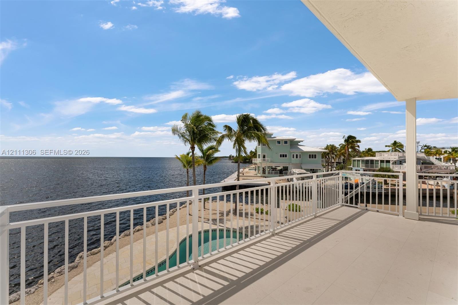 Covered balcony featuring white metal railings, tile flooring, and water frontage
