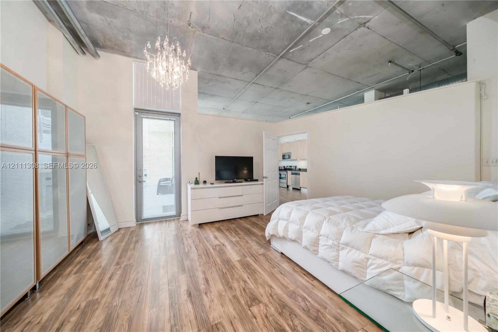 Exposed concrete ceiling, wood-finish flooring, glass-paneled entry door, crystal chandelier, and built-in closet cabinetry Exposed concrete ceiling, wood-finish flooring, glass-paneled entry door, crystal chandelier, and built-in closet cabinetry