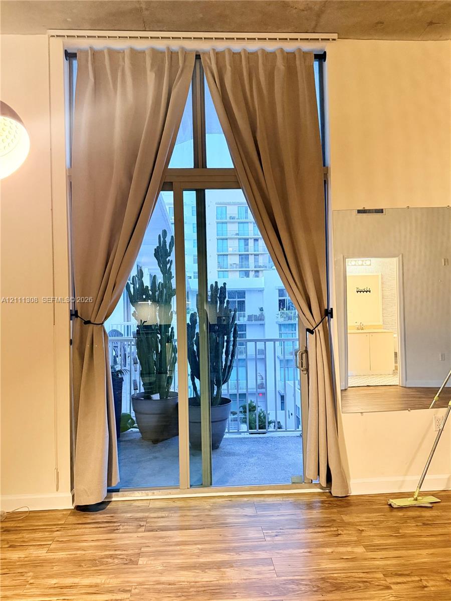 Floor-to-ceiling glass sliding doors, exposed concrete ceiling, wood-finish flooring, and private balcony Floor-to-ceiling glass sliding doors, exposed concrete ceiling, wood-finish flooring, and private balcony