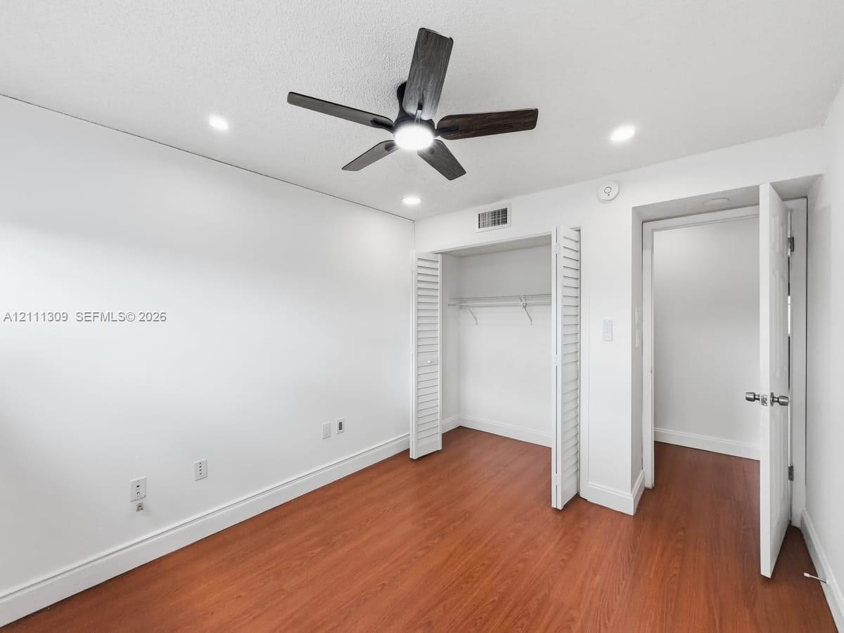 Room featuring wood-finish flooring, recessed lighting, a ceiling fan with integrated light, and a closet with bifold doors