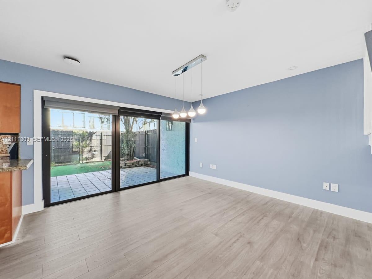 Expansive multi-panel sliding glass door, wood-finish flooring, linear four-light pendant fixture, and hardscaped patio