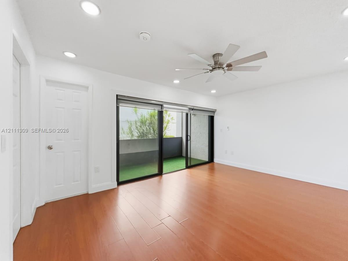 Interior space featuring wood-finish flooring, recessed lighting, a multi-blade ceiling fan, and sliding glass doors providing access to an exterior balcony