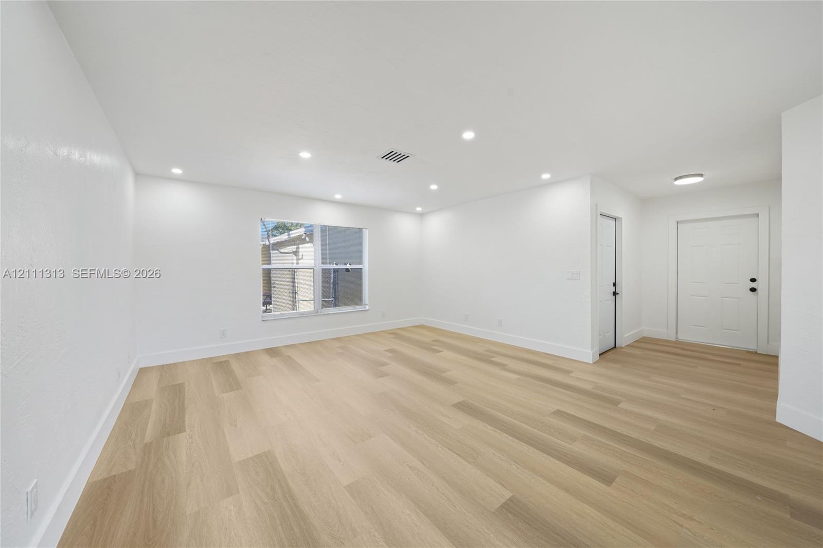 Open floor plan featuring wood-finish flooring, recessed lighting, and a multi-panel entry door