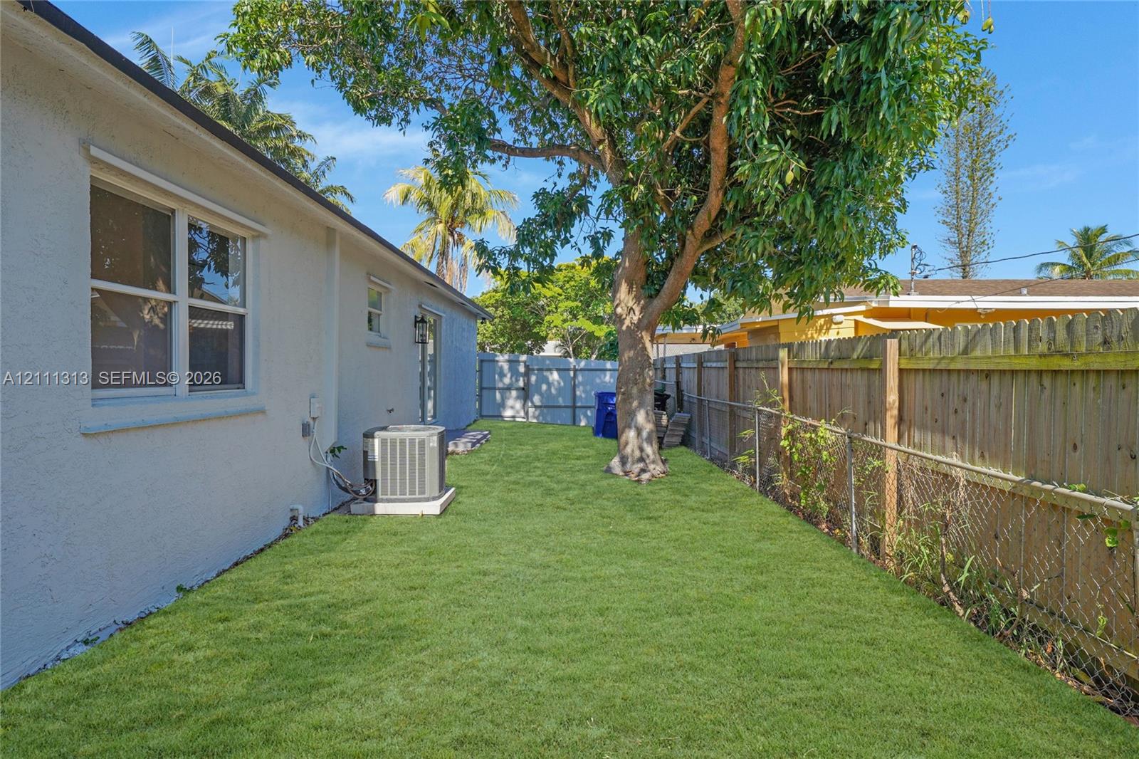 Side yard featuring a grass lawn, mature tree, and wood privacy fencing