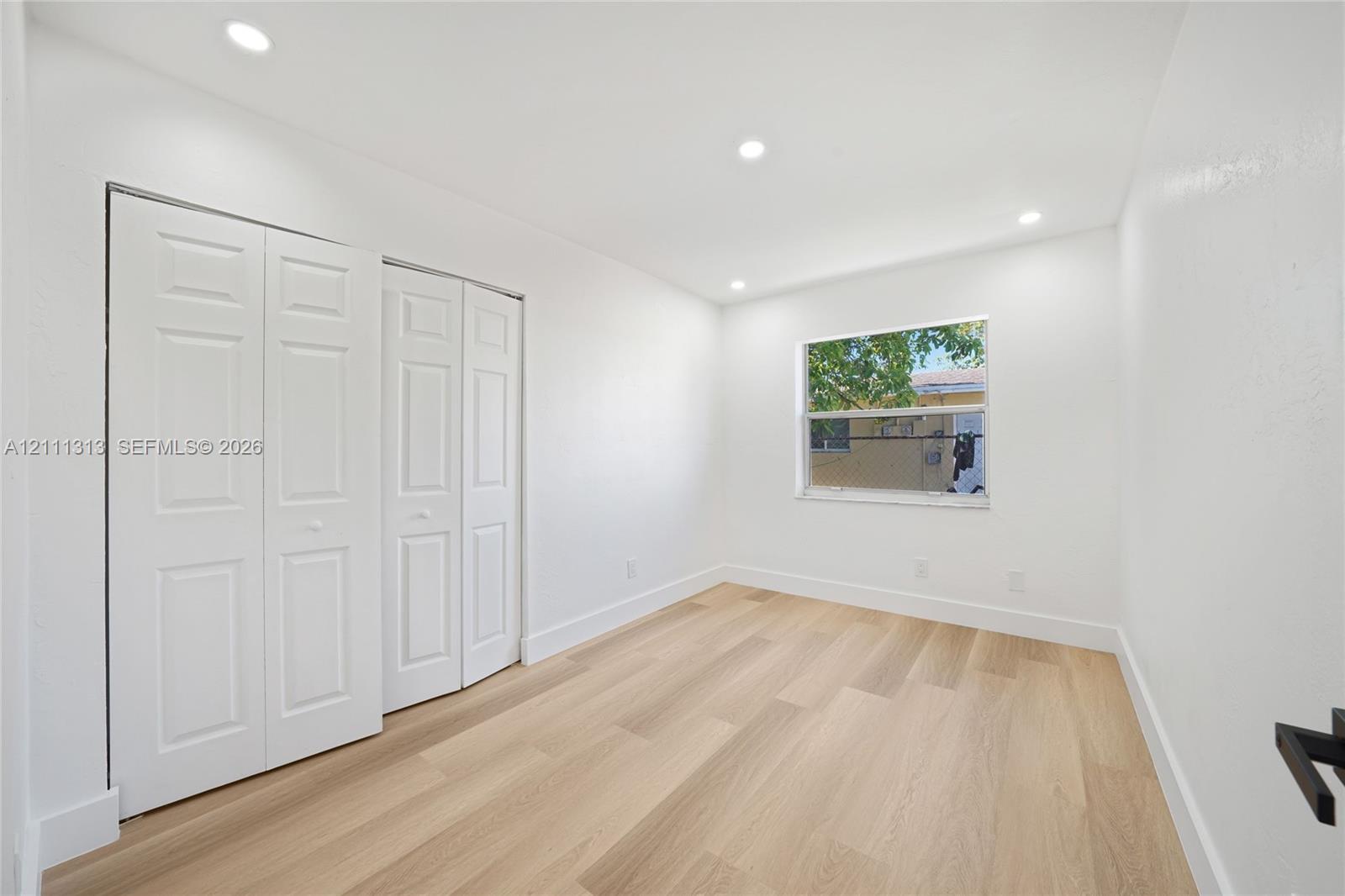 Wood-finish flooring, recessed lighting, and white panel bi-fold closet doors