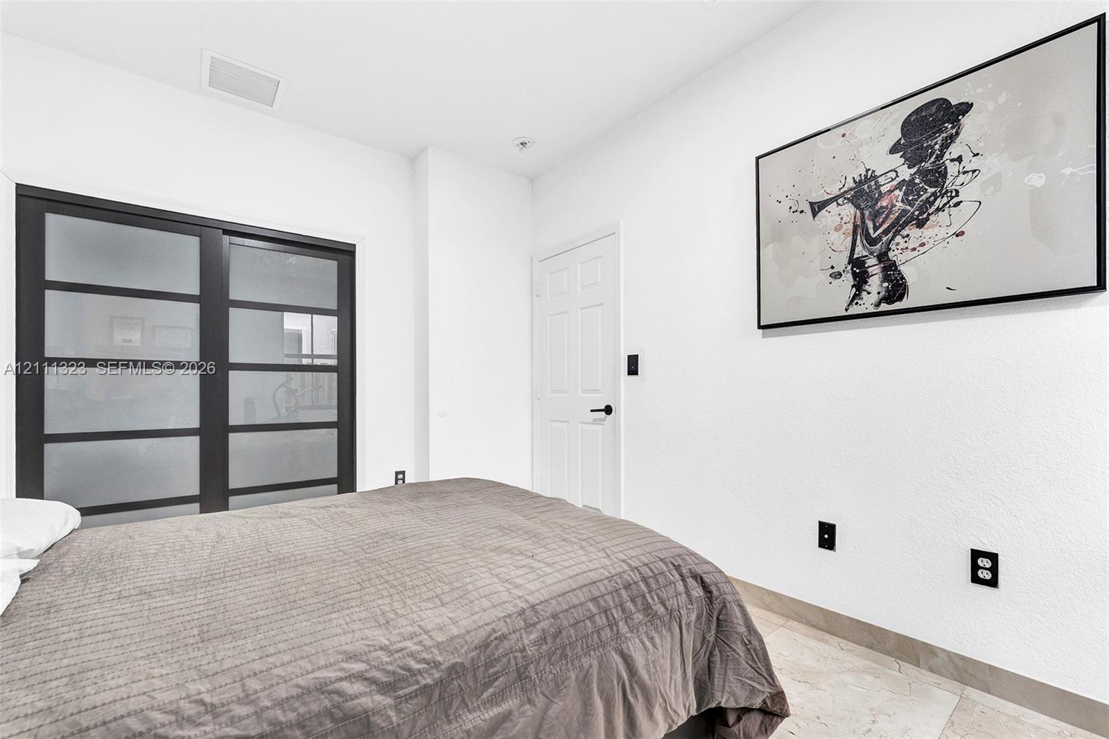 Sliding glass closet doors with dark frames and frosted panels, complemented by neutral tile flooring and a six-panel interior door