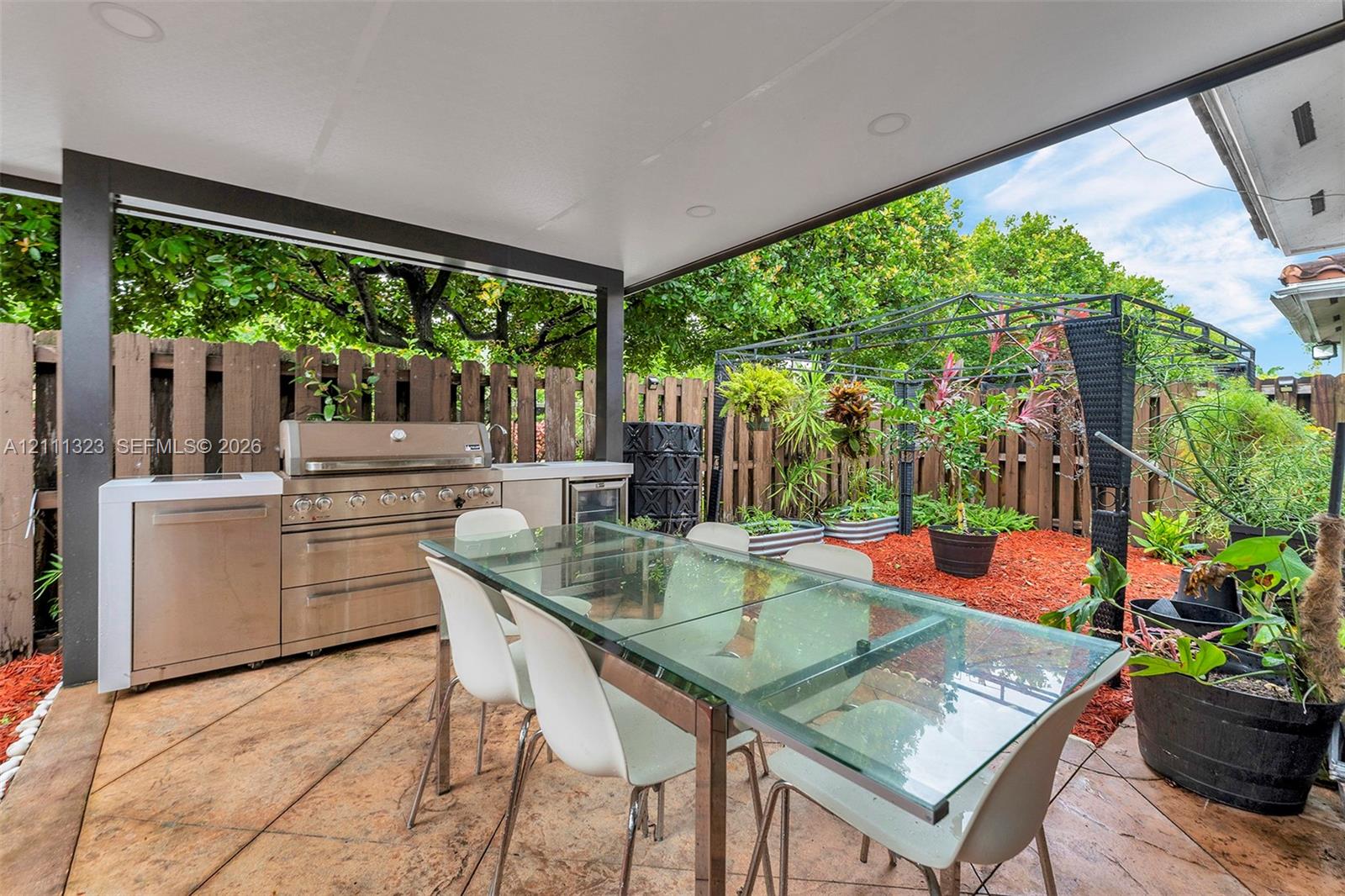 Covered patio featuring stamped concrete flooring, stainless steel outdoor kitchen, built-in beverage refrigerator, and recessed lighting