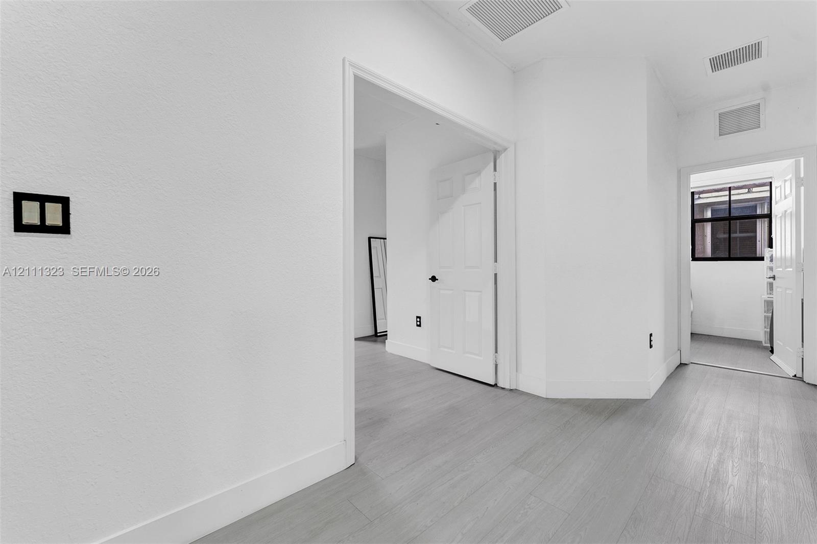 Interior space featuring wood-finish flooring, white walls, and paneled interior doors with matte black hardware