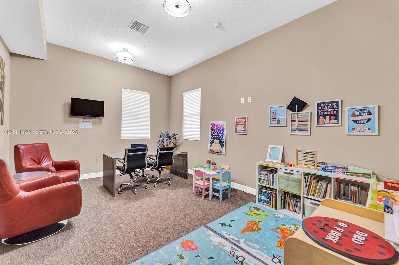 Multi-purpose room featuring high ceilings, two flush-mount light fixtures, neutral wall paint, and two windows with blinds