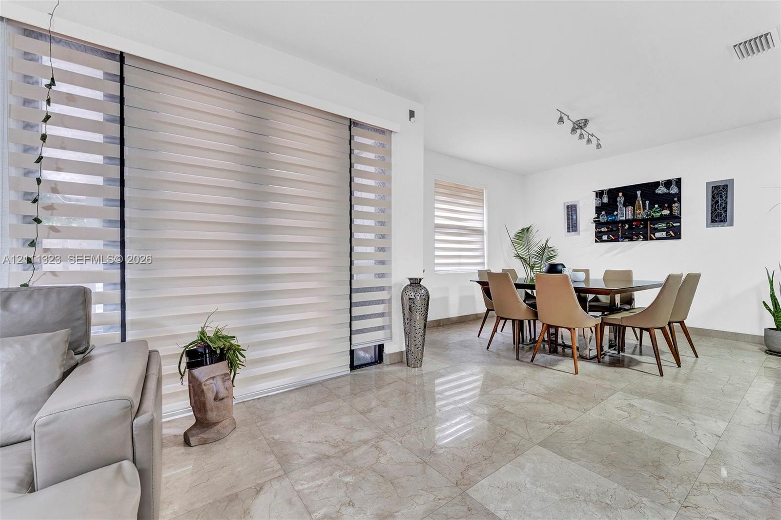 Large-format tile flooring, oversized sliding glass doors, and dual-layered window shades