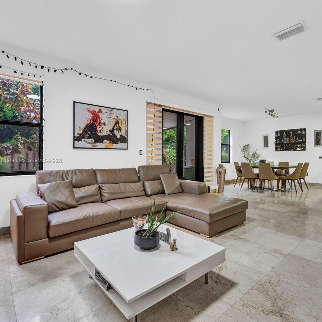 Open-concept interior featuring large-format stone flooring, floor-to-ceiling windows, and multi-panel exterior glass doors