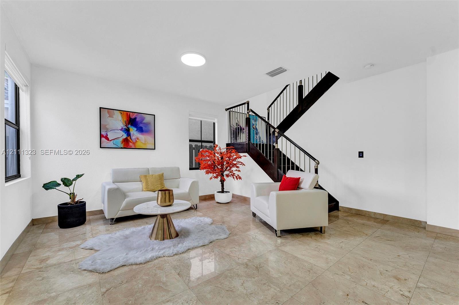 Open-concept area featuring polished tile flooring, a skylight, and a staircase with wooden treads and metal balusters