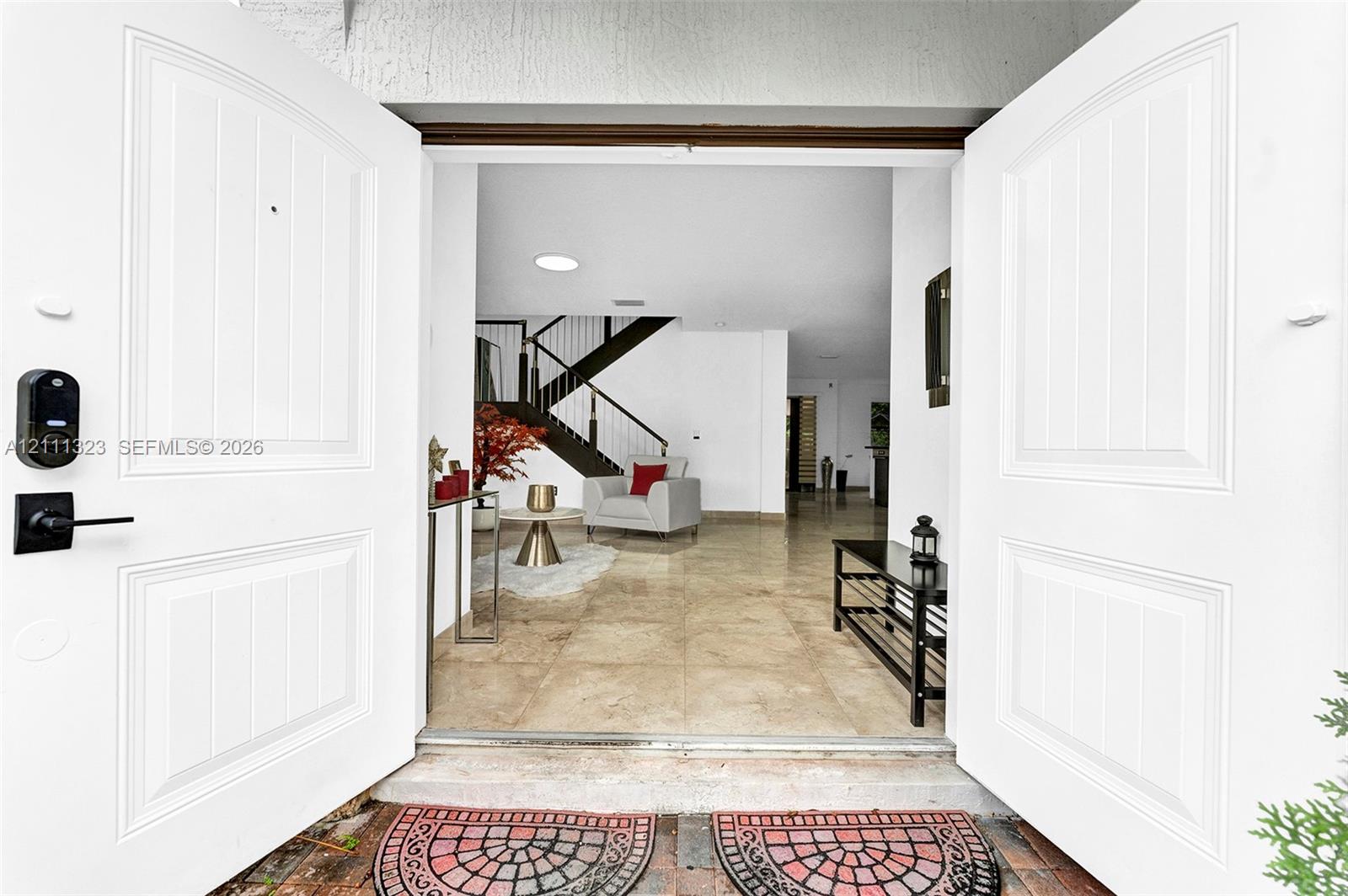Double-door entry featuring recessed lighting, stone flooring, and a staircase with dark-toned metal railings