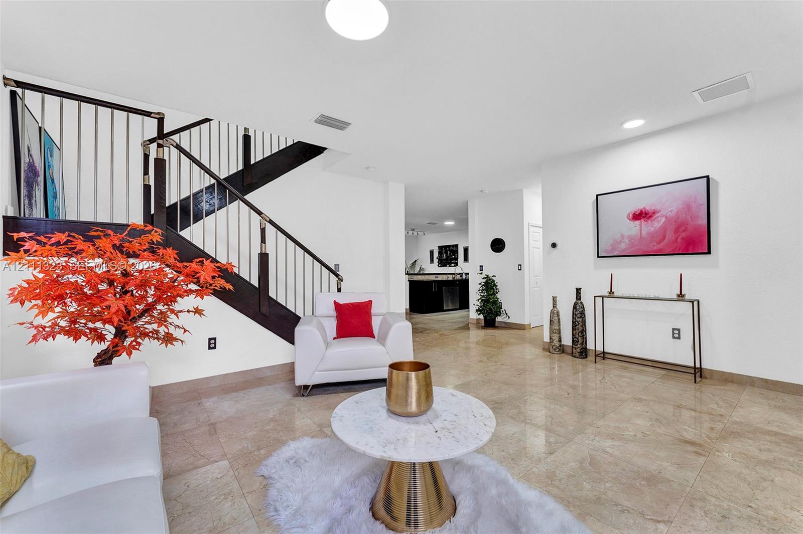 Open-concept interior featuring large-format tile flooring, recessed lighting, and a staircase with dark wood handrails and vertical metal balusters