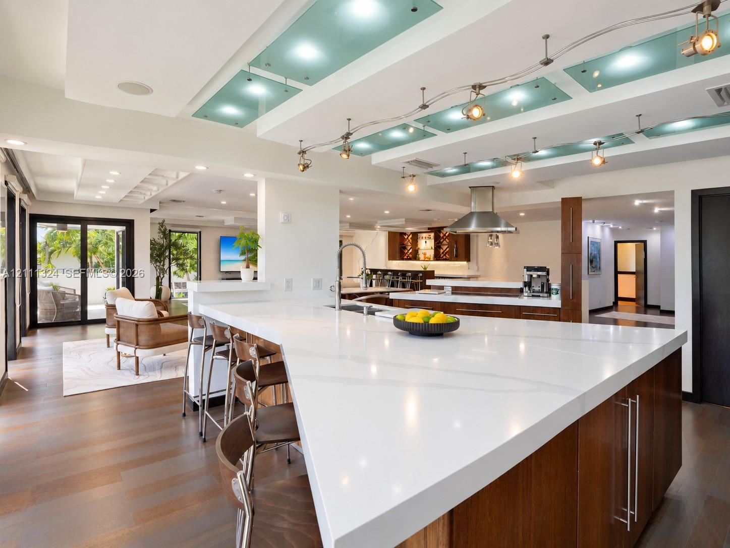 Kitchen featuring an oversized island with a solid surface countertop, wood-finish cabinetry, stainless steel range hood, recessed ceiling lighting with frosted glass panels, and wood-finish flooring