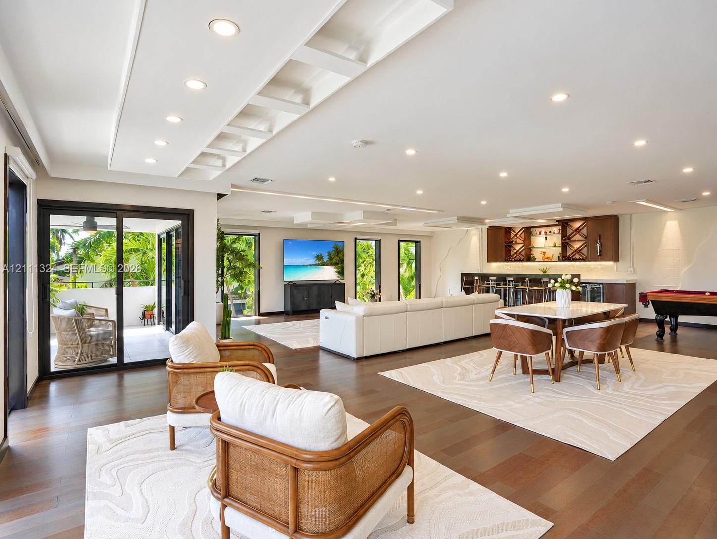 Spacious interior featuring recessed lighting, tiered tray ceilings, wood-finish flooring, and a built-in wet bar with cabinetry