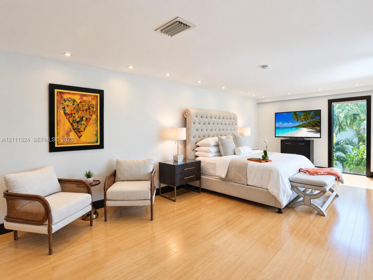Light-filled bedroom featuring wood-finish flooring, recessed lighting, and a glass-paneled door