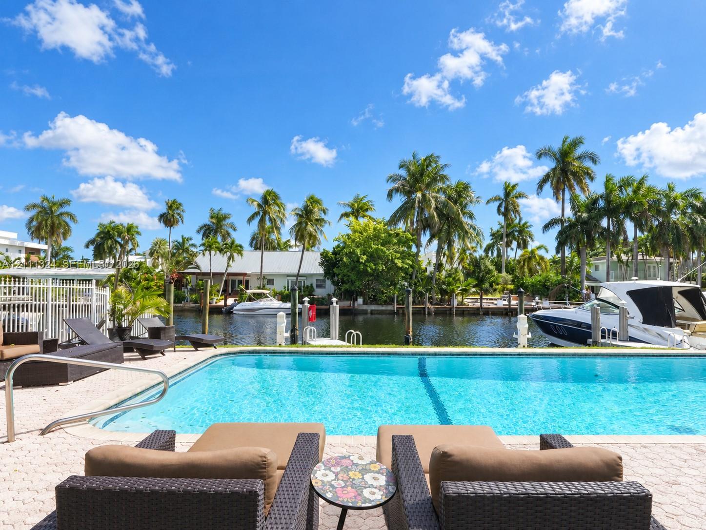 Waterfront swimming pool with a paved patio, metal safety fencing, and private boat dockage