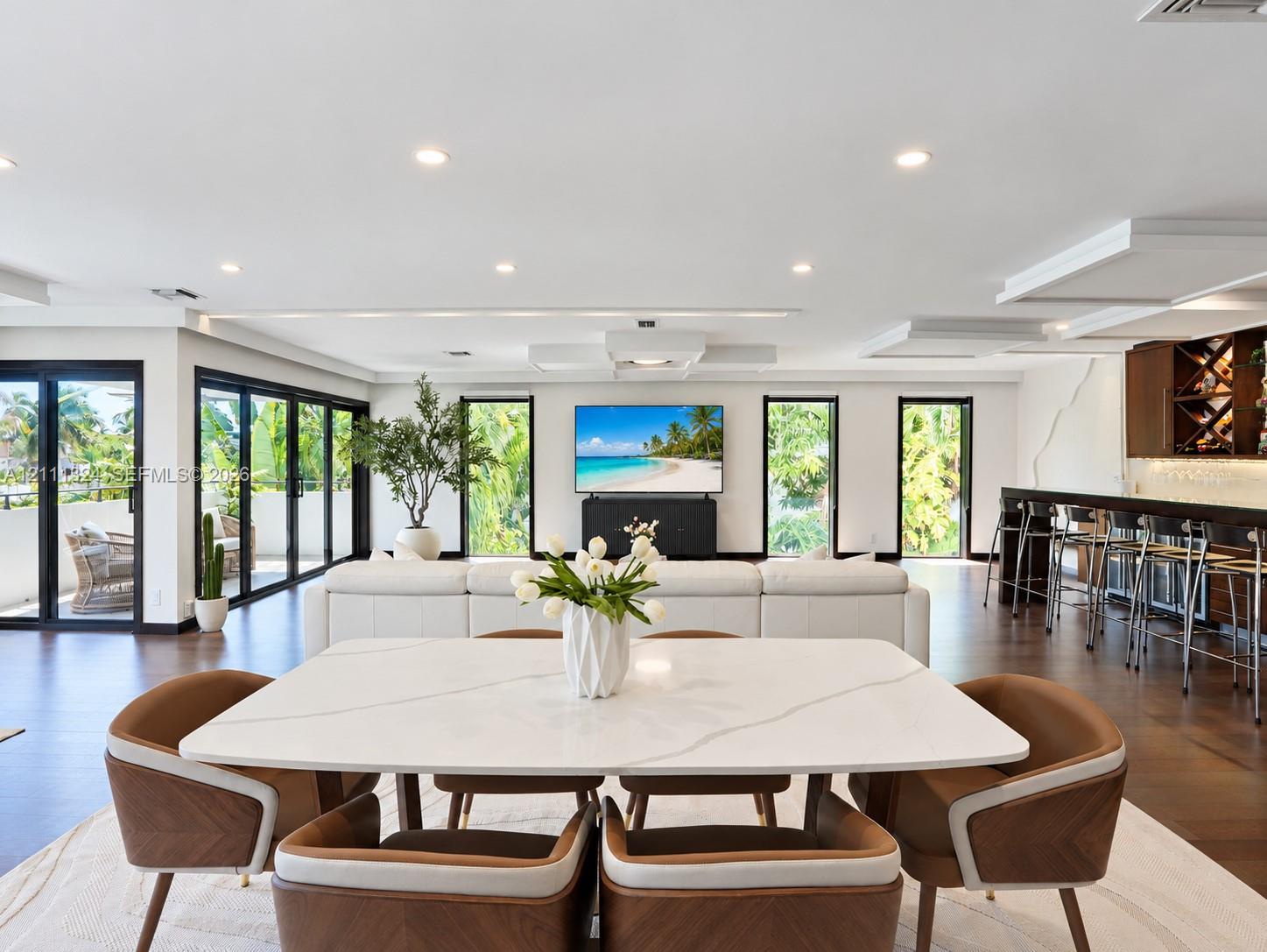 Open-concept interior featuring recessed lighting, dark wood-finish flooring, multi-panel sliding glass doors, and a built-in wet bar with cabinetry