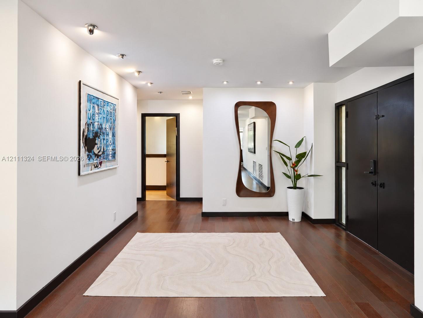 Interior space featuring dark wood-finish flooring, recessed ceiling lighting, and matte black door trim