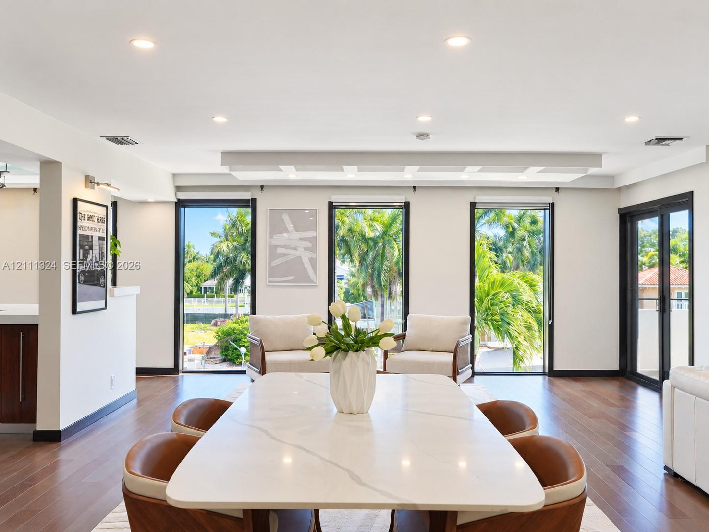 Open-concept interior featuring recessed lighting, a coffered ceiling, wood-finish flooring, and floor-to-ceiling glass panel doors