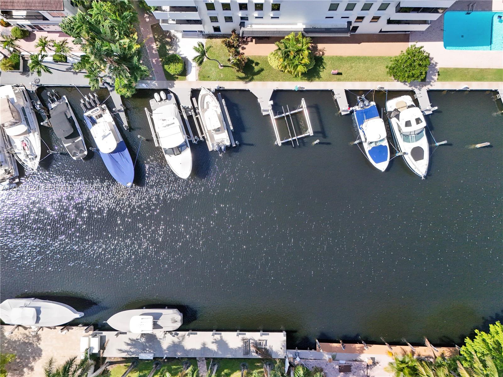 Deep-water canal frontage featuring multiple concrete bulkhead docks, boat slips, and a swimming pool