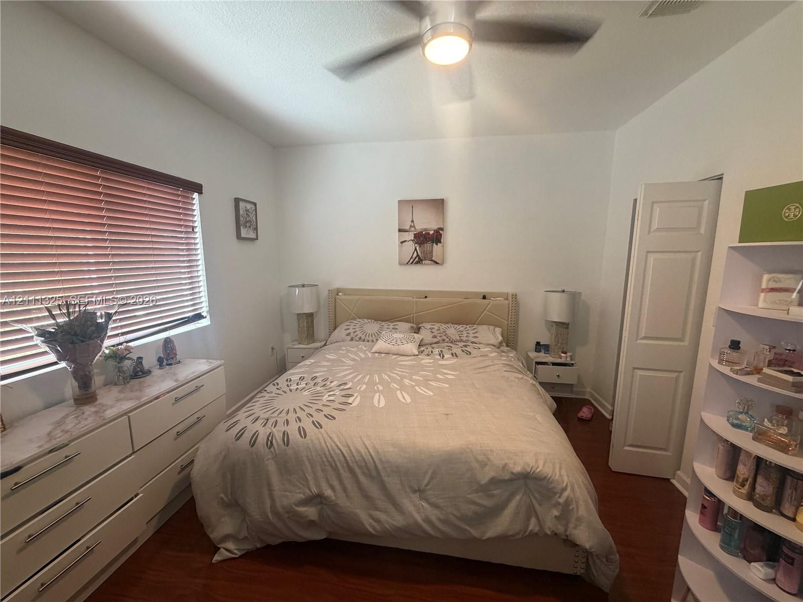 Interior space featuring wood-finish flooring, a ceiling-mounted light fixture with integrated fan, and horizontal window blinds