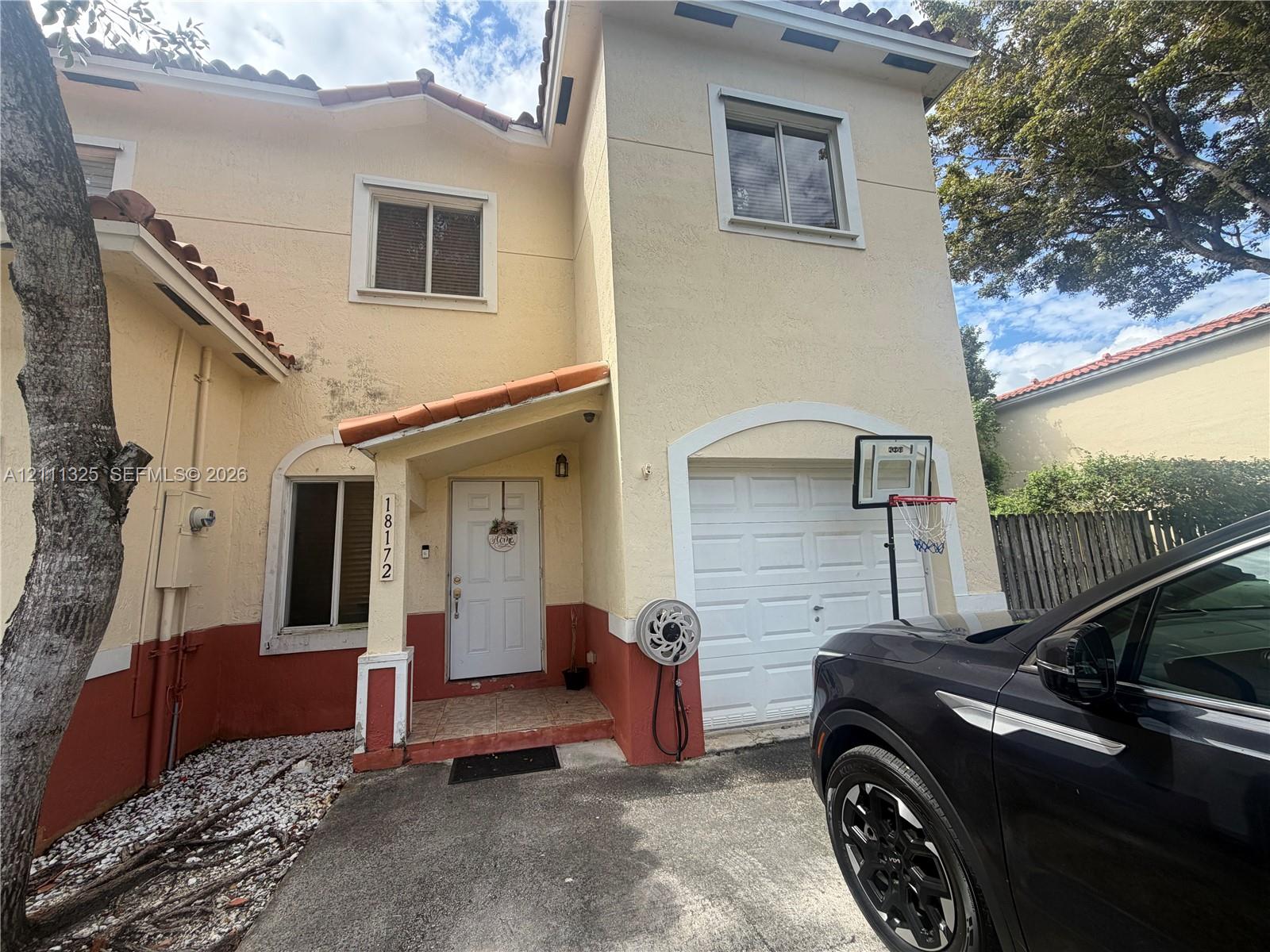 Two-story exterior featuring a stucco faade, tile roof accents, covered entryway, and an attached one-car garage