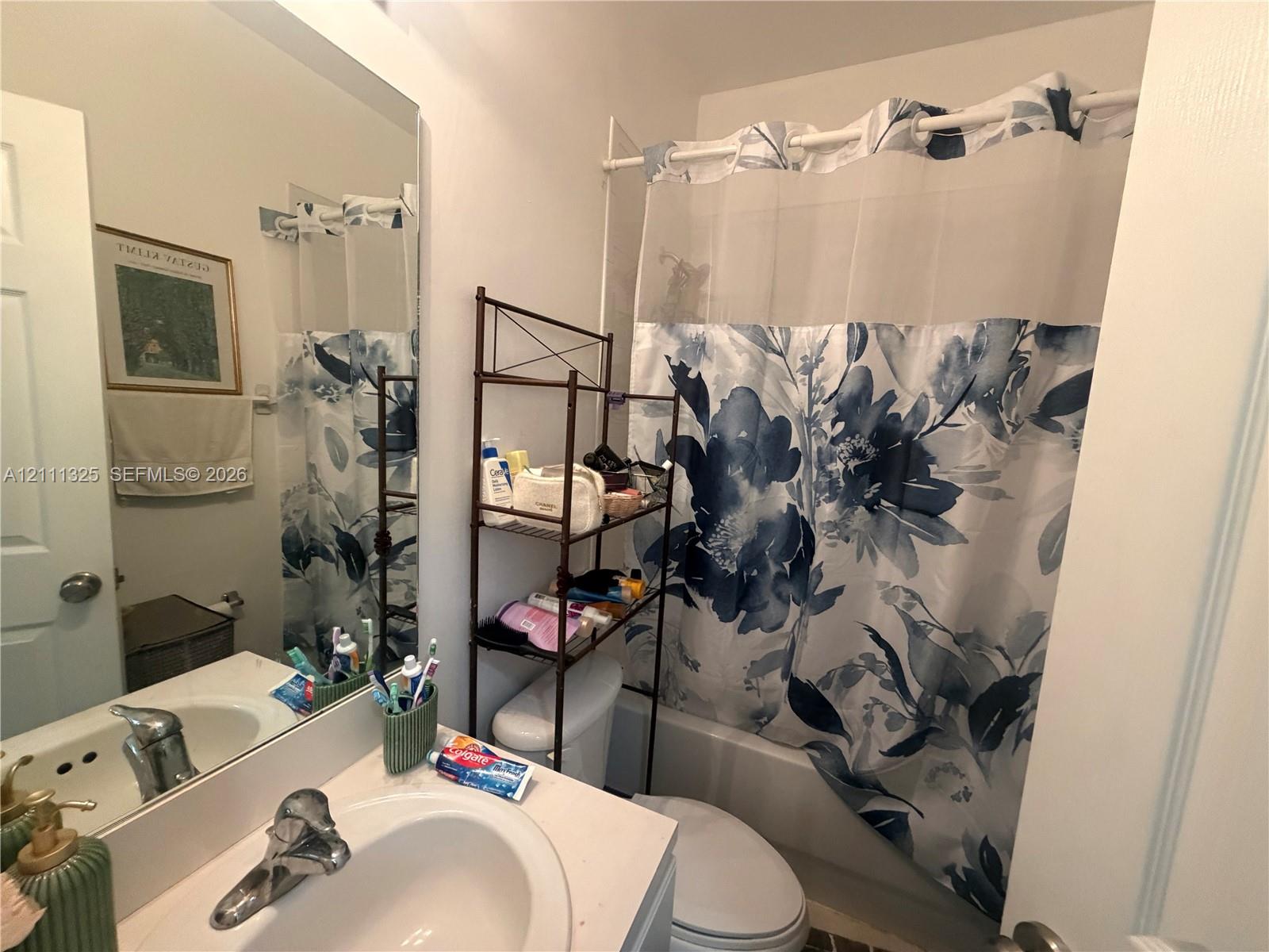 Bathroom featuring a vanity with a recessed oval basin, chrome-finish faucet, and a wall-mounted rectangular mirror over a bathtub and shower combination