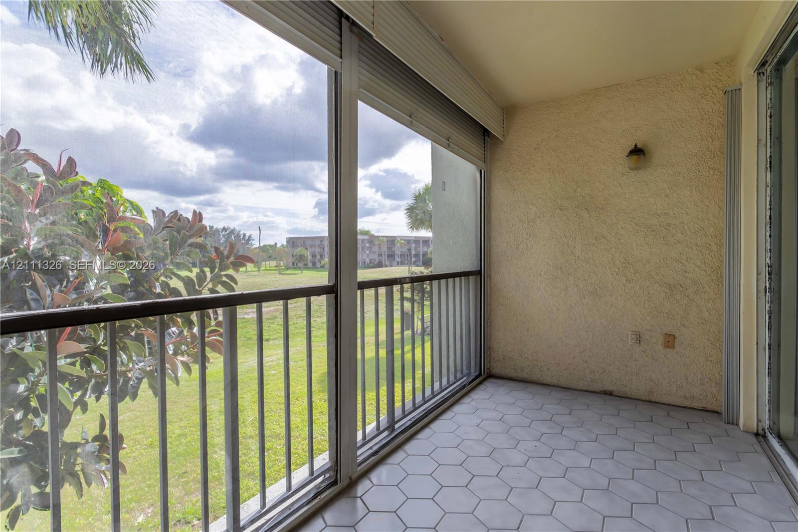 Screened-in balcony featuring hexagonal tile flooring, metal railings, textured wall finish and beautiful view.