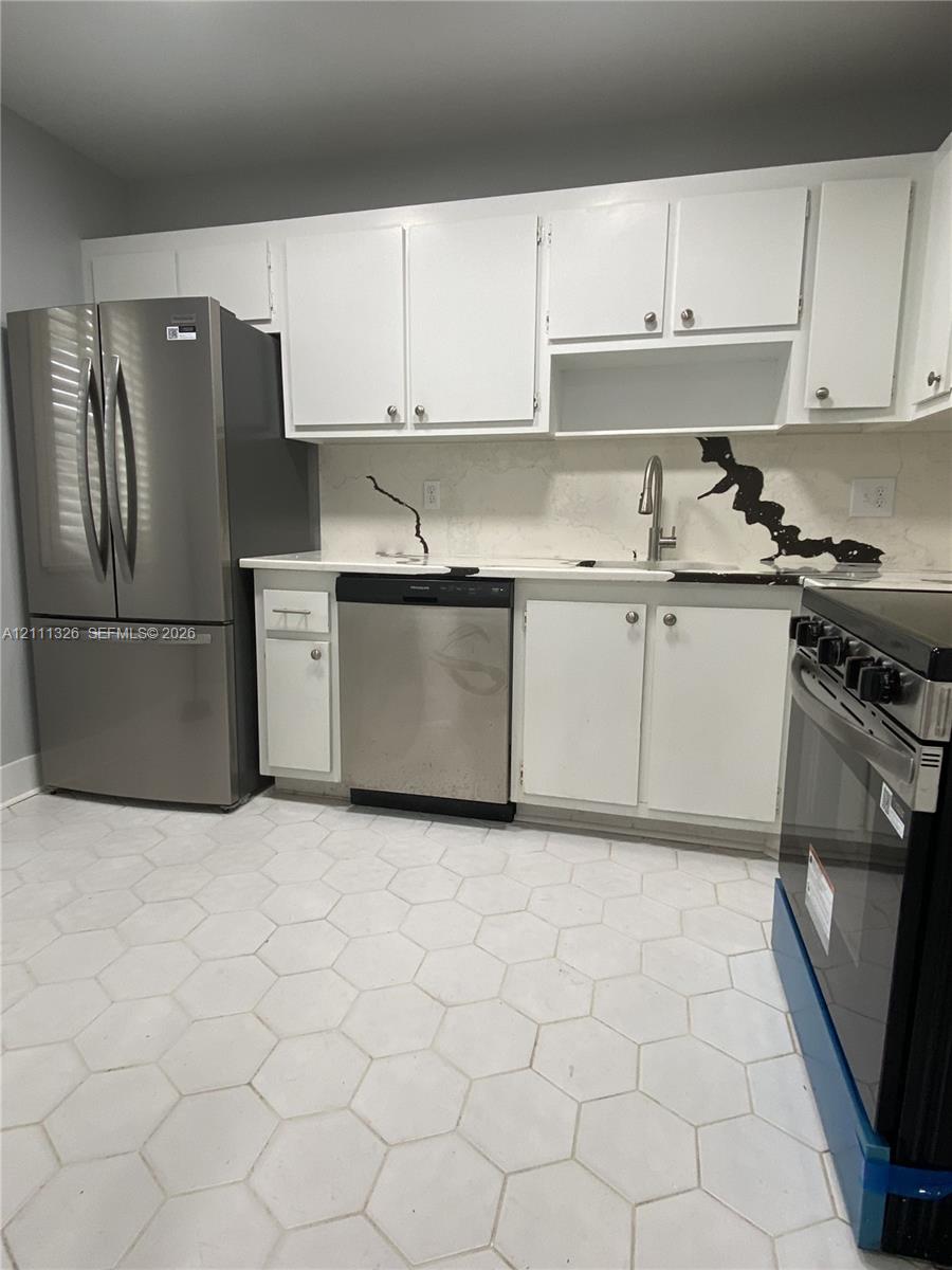 Kitchen featuring brand new stainless steel appliances, white shaker-style cabinetry, stone-finish countertops with matching backsplash, and hexagonal tile flooring. Kitchen featuring brand new stainless steel appliances, white shaker-style cabinetry, stone-finish countertops with matching backsplash, and hexagonal tile flooring.