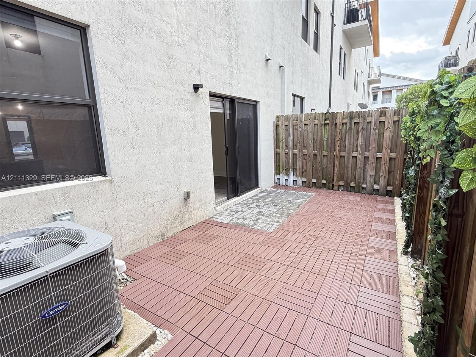 Private patio area featuring modular wood-composite decking, paver stone section, and wood privacy fencing
