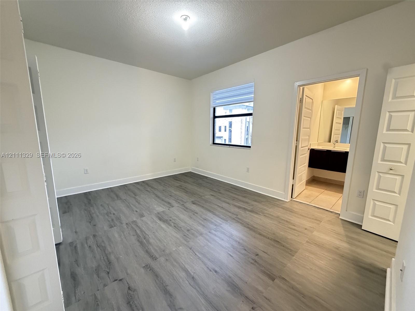 Room featuring wood-finish flooring, recessed lighting, white panel doors, and a window with integrated blinds