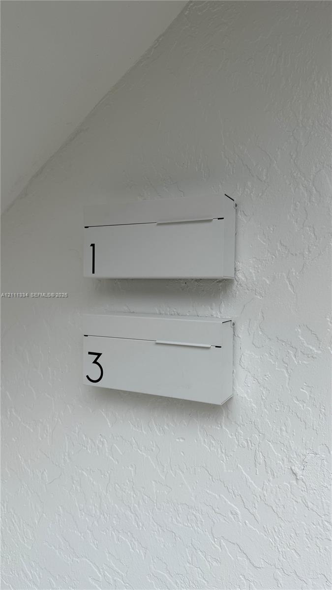 Wall-mounted, matte-finished white metal mailboxes featuring minimalist numeric lettering and a clean-lined rectangular design