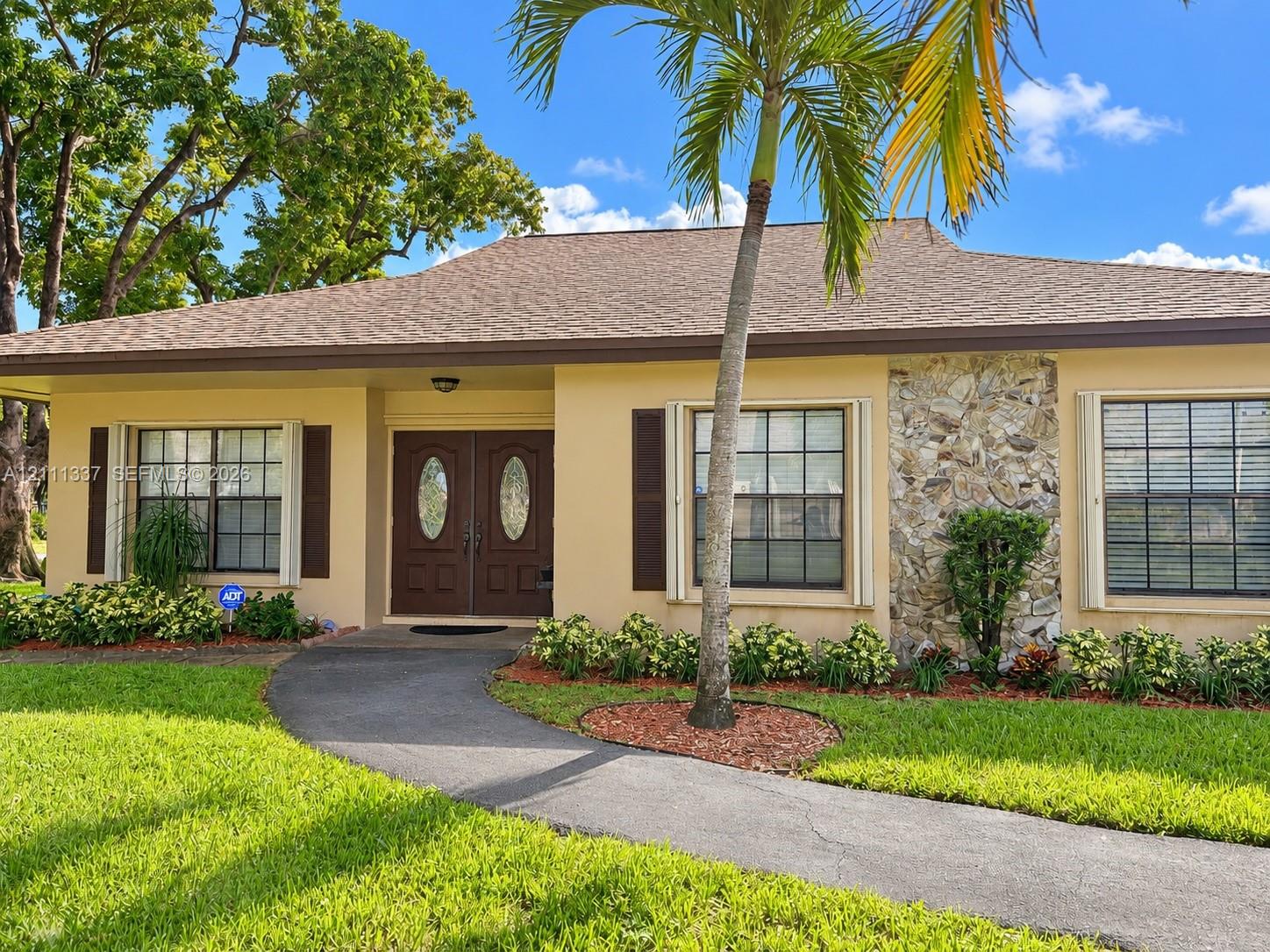 Single-story residence featuring a shingle roof, double-door entryway, exterior stone facade detailing, and shutter-framed windows Single-story residence featuring a shingle roof, double-door entryway, exterior stone facade detailing, and shutter-framed windows