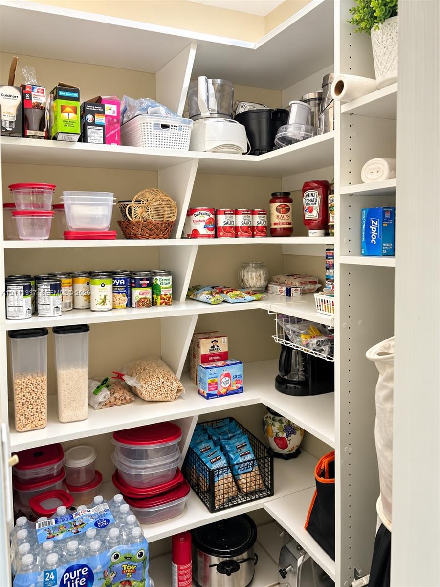 Walk-in pantry featuring white custom built-in shelving with adjustable height options
