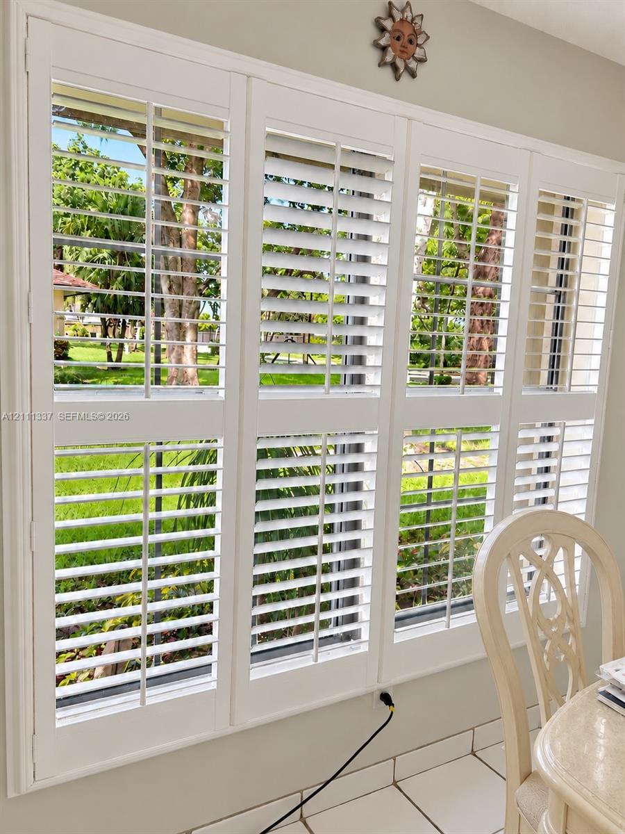 Large multi-panel window featuring white plantation shutters and light-toned ceramic tile flooring Large multi-panel window featuring white plantation shutters and light-toned ceramic tile flooring
