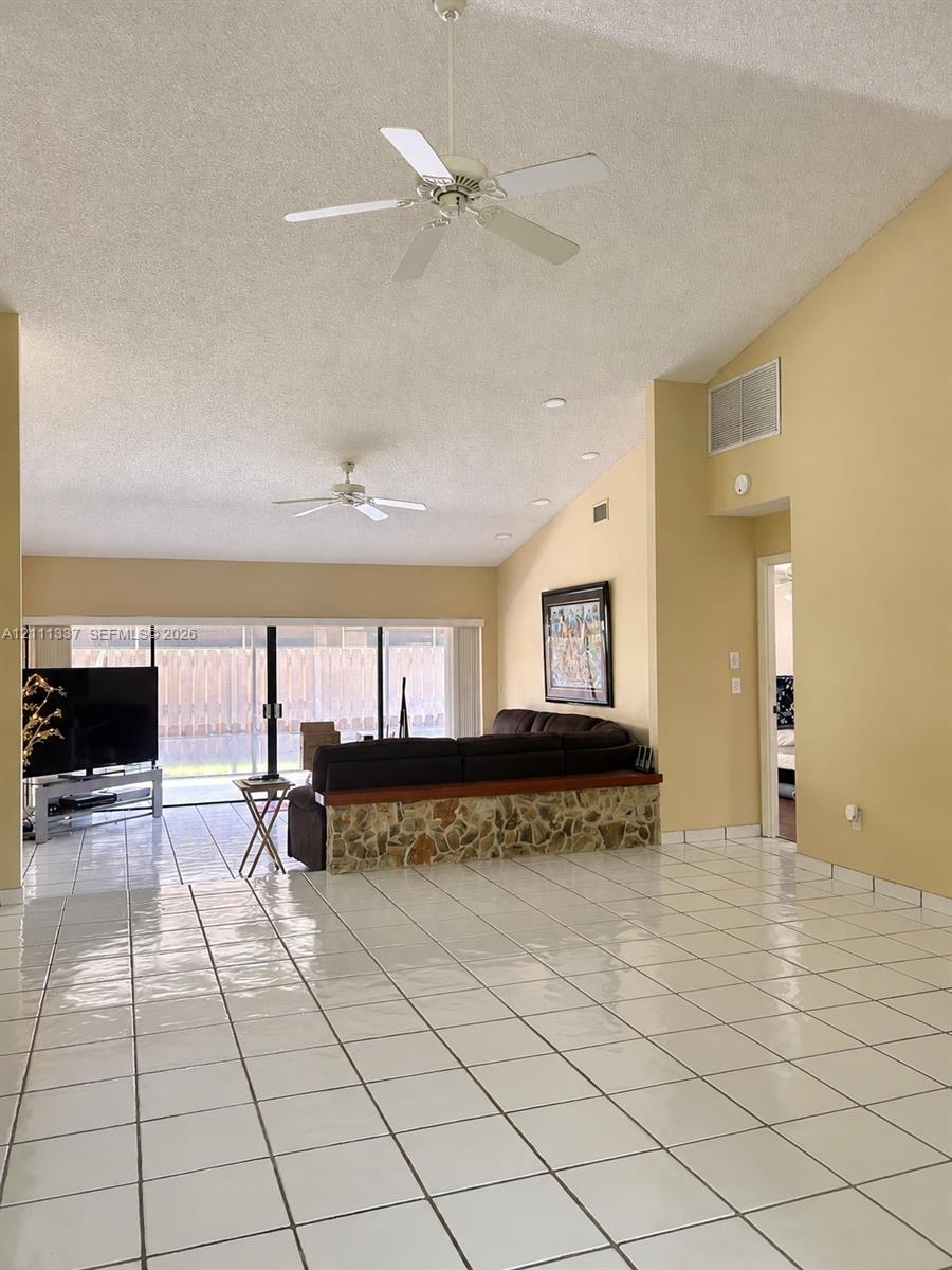 Vaulted ceilings, large-format tile flooring, dual ceiling fans, and sliding glass doors