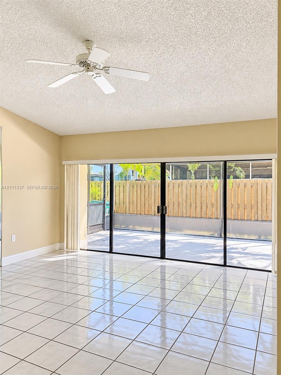 Large-format sliding glass doors, white ceramic tile flooring, and ceiling fan with integrated lighting Large-format sliding glass doors, white ceramic tile flooring, and ceiling fan with integrated lighting