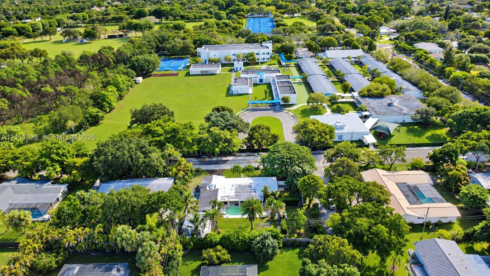Aerial perspective featuring a residential lot with an in-ground swimming pool and expansive surrounding green space